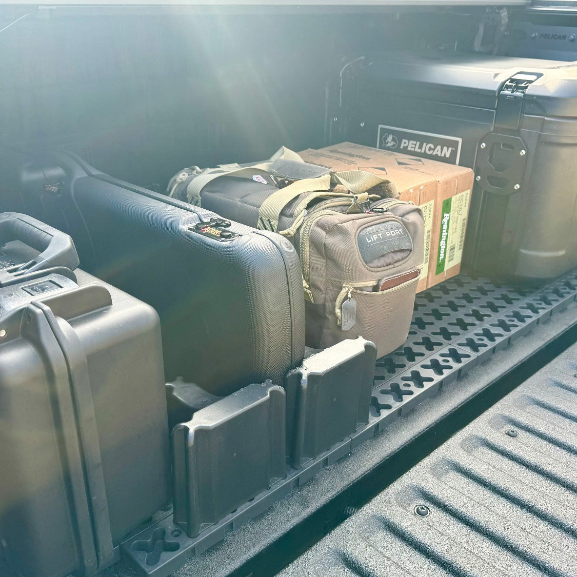 Gun cases and ammo arranged in the back of a truck bed.